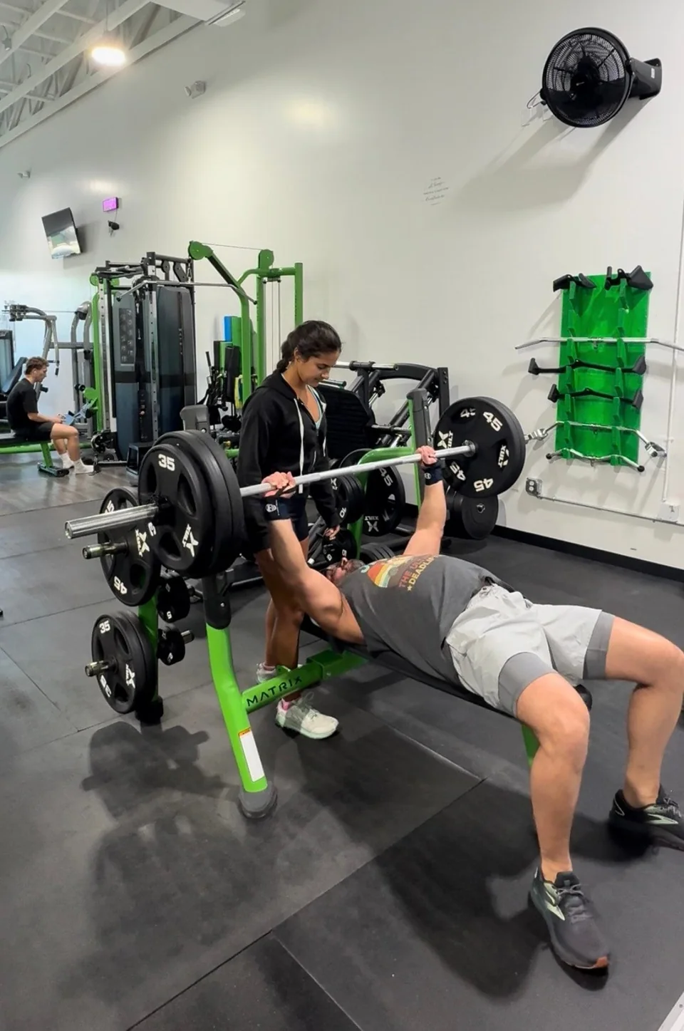 A spotter assisting a member with a bench press at Titan Gym